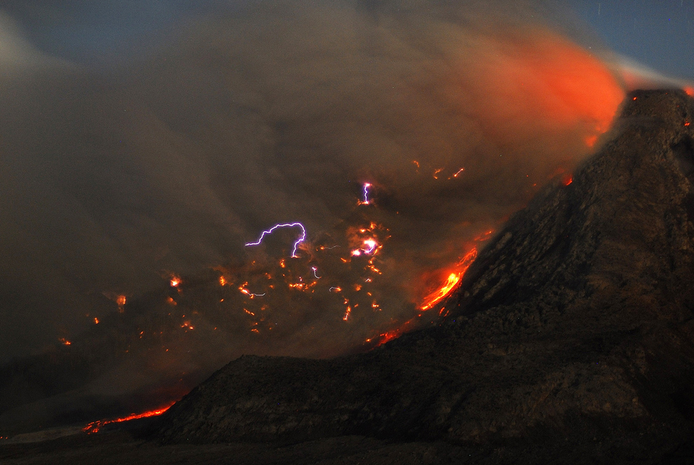 Fotografie cu expunere lungă realizată la apusului soarelui: Fulgere, lavă şi nori de cenuşă pot fi vazuţi în apropiere de craterul vulcanului Mount Sinabung din Karo, Indonezia, marţi, 14 octombrie 2014.