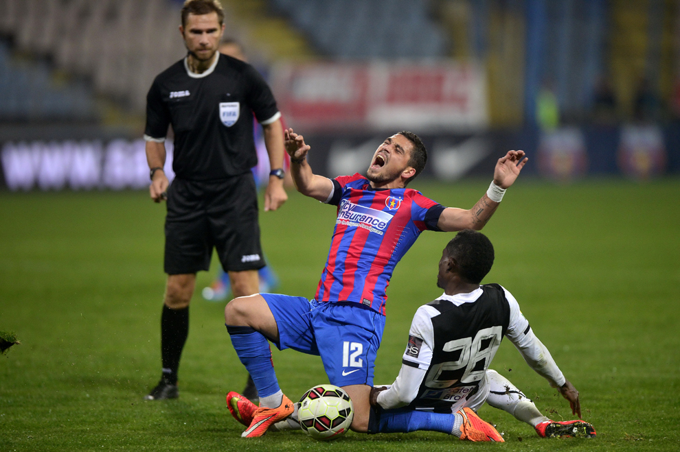 Jucătorii Nicolae Stanciu, de la Steaua Bucureşti, şi Justin Junior Mengolo, de la Universitatea Cluj, cad în timpul meciului din cadrul etapei a XI-a a Ligii I, disputat în Bucureşti, duminică, 19 octombrie 2014.