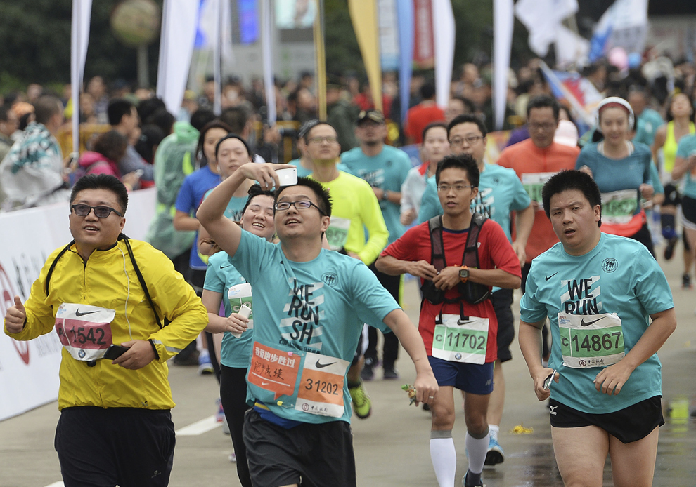 Un bărbat îşi face un selfie în timp ce trece linia de sosire a Maratonului Internaţional Shanghai, 2 noiembrie, 2014.
