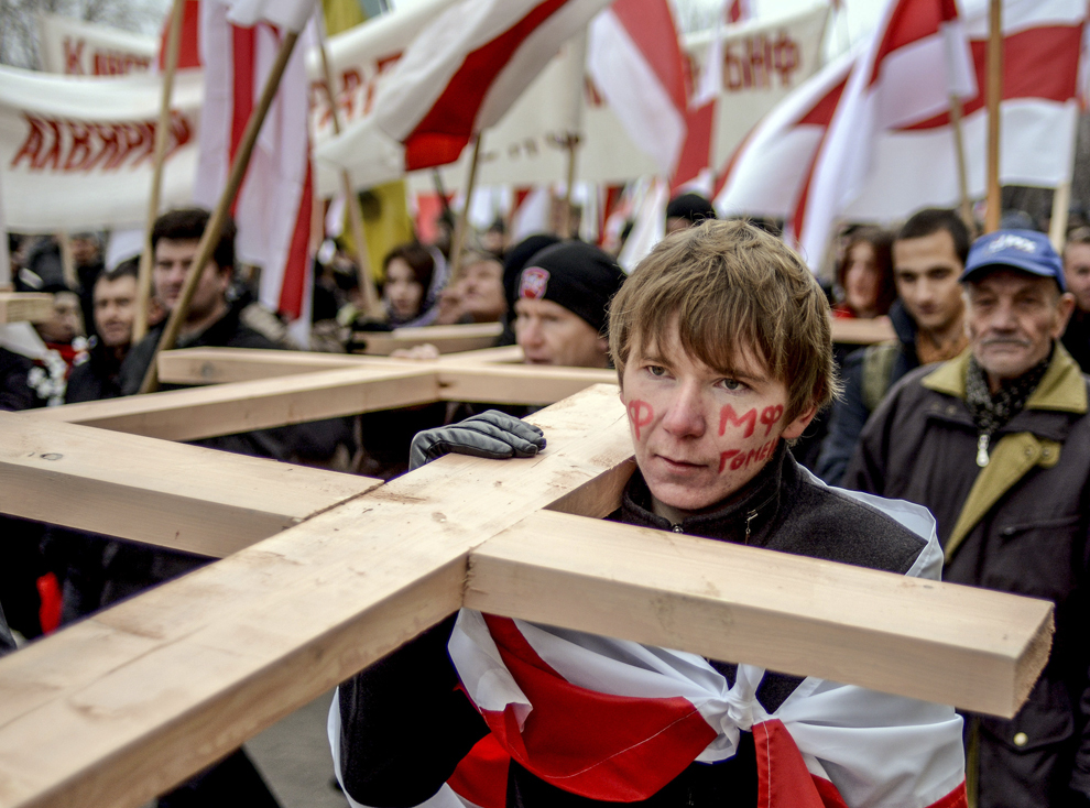 Suporteri ai opoziţiei transportă cruci în timp ce flutură steagurile naţionale ale Belarusului,  în timpul unui marş către o groapă comună unde erau îngropate persoanele executate în perioada stalinistă, la periferia oraşului Minsk, Belarus, duminică, 2 noiembrie 2014.