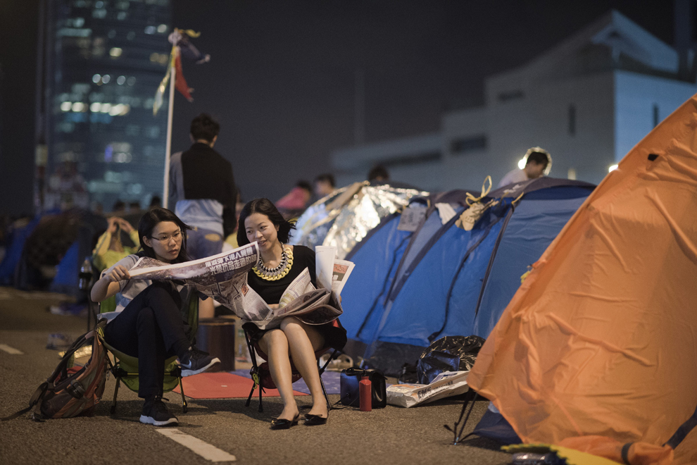 Protestatari pro-democraţie citesc un ziar în zona în care protestează, în districtul Amiralităţii din Hong Kong, luni, 27 octmbrie 2014.