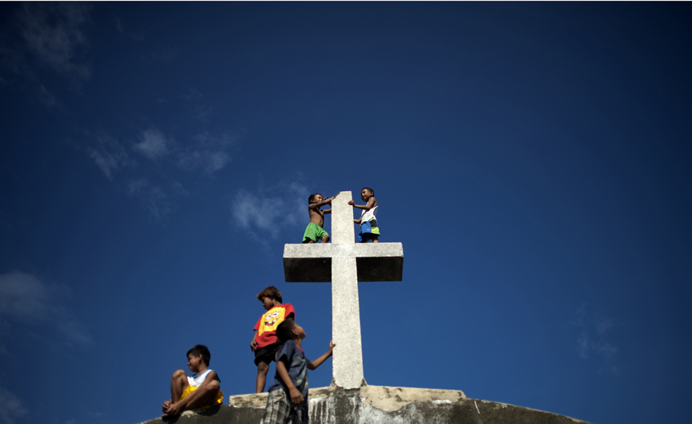 Copii ce locuiesc în cimitirul public Navotas din Manila, se urcă pe o cruce, vineri, 31 octombrie 2014. 