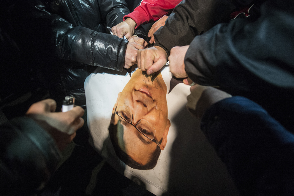 Tineri rup un banner al candidatului la preşedinţie, Victor Ponta în timpul unui miting, după anunţarea rezultatelor exit-poll-urilor la alegerile prezidenţiale, în Bucureşti, duminică, 16 noiembrie 2014.