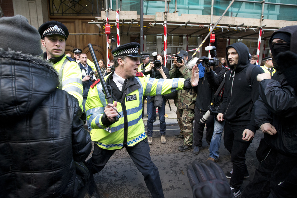 Un ofiţer de poliţie se confruntă cu protestatari aflaţi în faţa sediului central de campanie a Partidului Conservator, la finalul unui marş împotriva introducerii taxelor de înscriere la facultate, în Londra, miercuri, 19 noiembrie 2014. 