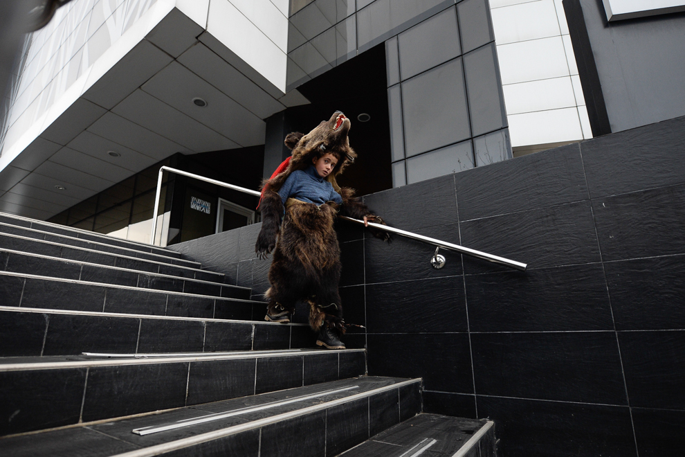 Un copil, costumat în urs, din comuna Dofteana, judeţul Bacău, coboară treptele unei clădiri de birouri, în centrul Bucureştiului, marţi, 23 decembrie 2014. 