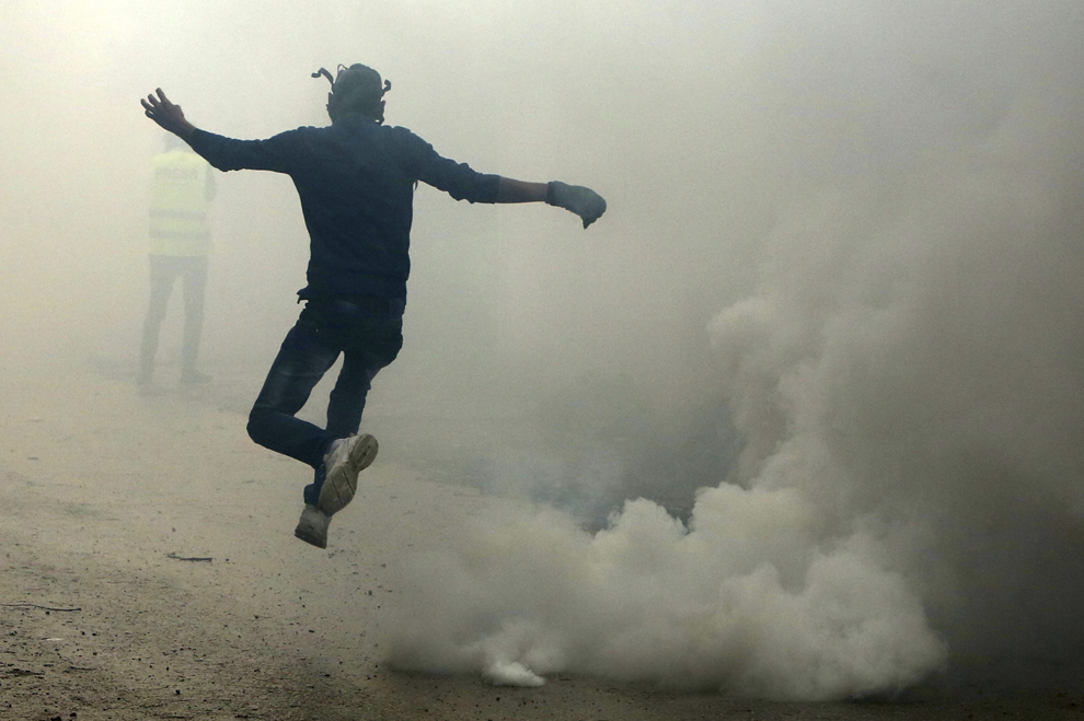Un protestatar palestinian fuge din calea gazelor lacrimogene, în timpul unor ciocniri cu forţele de securitate israeliene desfăşurate în timpul unui protest, în Kfar Qaddum, în apropiere de Nablus, în Cisiordania, vineri, 16 ianuarie 2015.