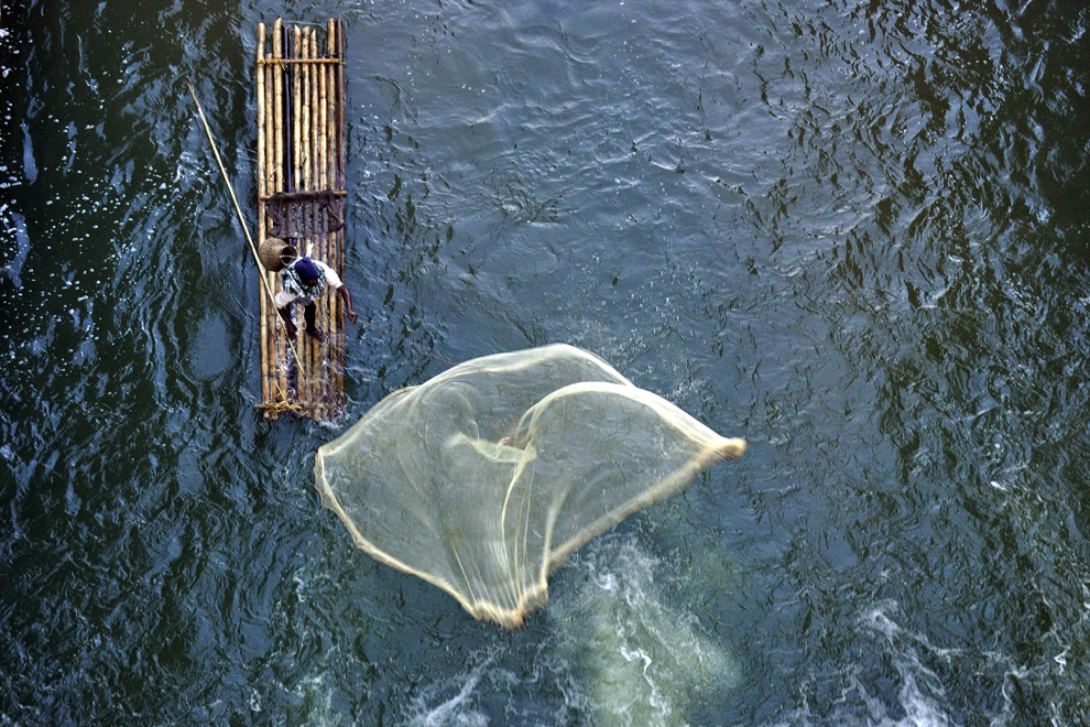 Un pescar aruncă năvodul în apropierea unei ecluze de pe râul Hovra ce traversează localitatea Chakmaghat, în provincia Tripura din India, joi, 15 ianuarie 2015.