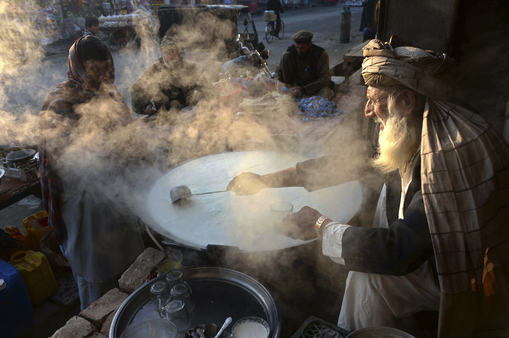 Un comerciant afgan fierbe lapte în timp ce aşteaptă clienţi, în Jalalabad, provincia Nangarhar, vineri, 16 ianuarie 2015.