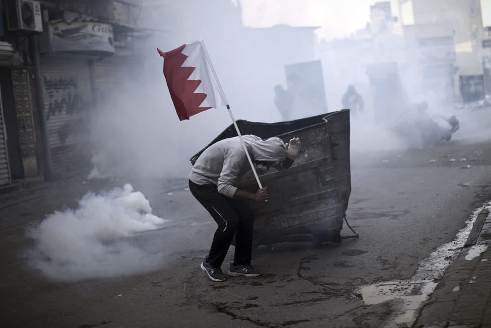 Un protestatar se ascunde în timpul unor ciocniri cu forţele de ordine, în timpul unui protest împotriva arestarii lui Sheikh Ali Salman, în satul Bilad al-Quadeem, Bahrain, marţi, 20 ianuarie 2015.