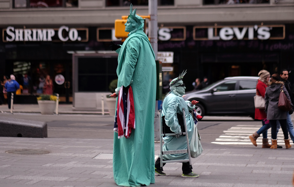 Doi barbaţi costumaţi în Statuia Libertatii aşteaptă clienţi, în Times Square din New York, marţi, 20 ianuarie 2015.