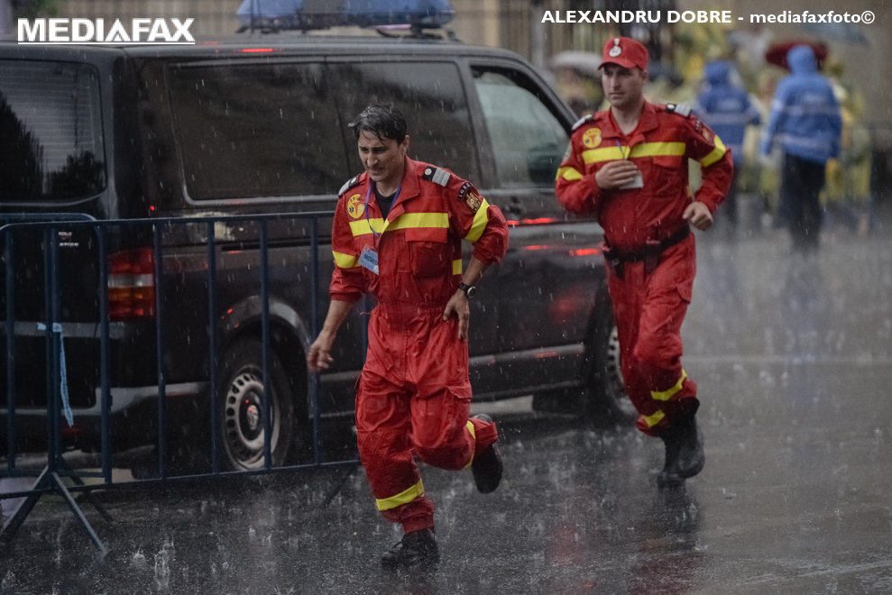 Doi paramedici incearca sa se adaposteasca de ploaie in timpul vizitei Papei Francisc in Bucuresti, vineri 31 mai 2019. ALEXANDRU DOBRE / MEDIAFAX FOTO