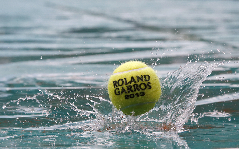 O minge oficială a turneului de tenis Roland Garros de la Paris sare pe suprafaţa de joc acoperită cu apă, în timpul unei ploi torenţiale, joi, 30 mai 2013.  