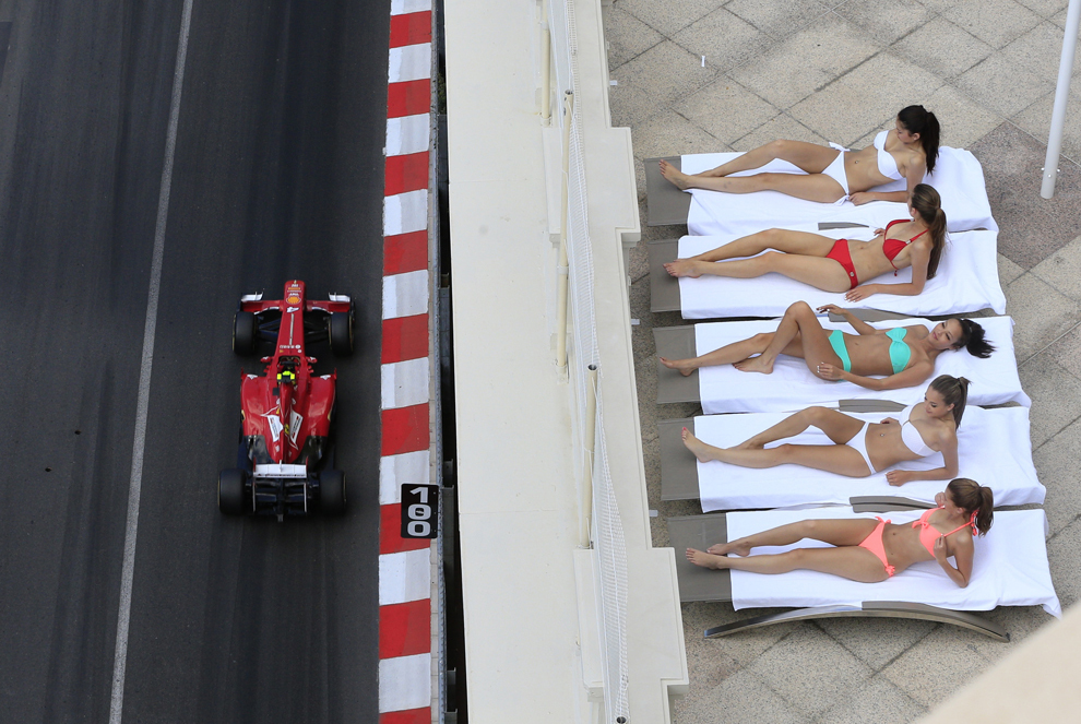 Mai multe tinere fac plajă în timp ce pilotul brazilian al echipei Ferrari, Felipe Massa participă la cea de-a treia sesiune de antrenamente, pe circuitul din Monaco, înaintea Marelui Premiu de Formula 1, sâmbătă, 25 mai 2013.  