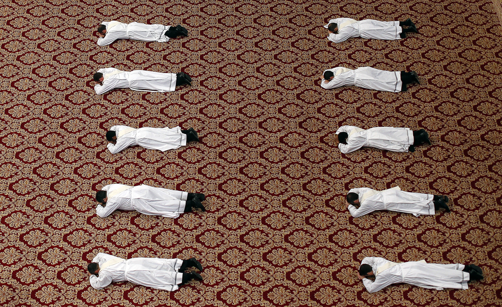Preoţi se prosternează în faţa altarului, în timpul unei slujbe oficiate de Papa Francis, duminică, 21 aprilie 2013.  