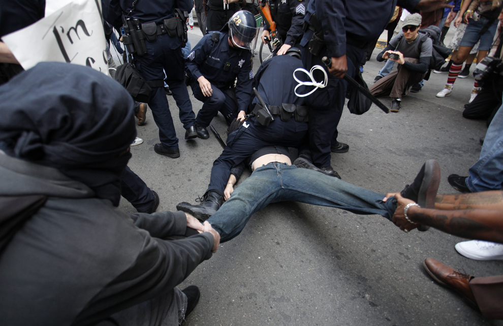 Activişti ce fac parte din mişcarea Occupy Wall Street, încearcă să salveze un protestatar reţinut de poliţie, în timpul unui miting organizat cu ocazia Zilei Internaţionale a Muncitorilor, în Oakland, marţi, 1 mai 2012.