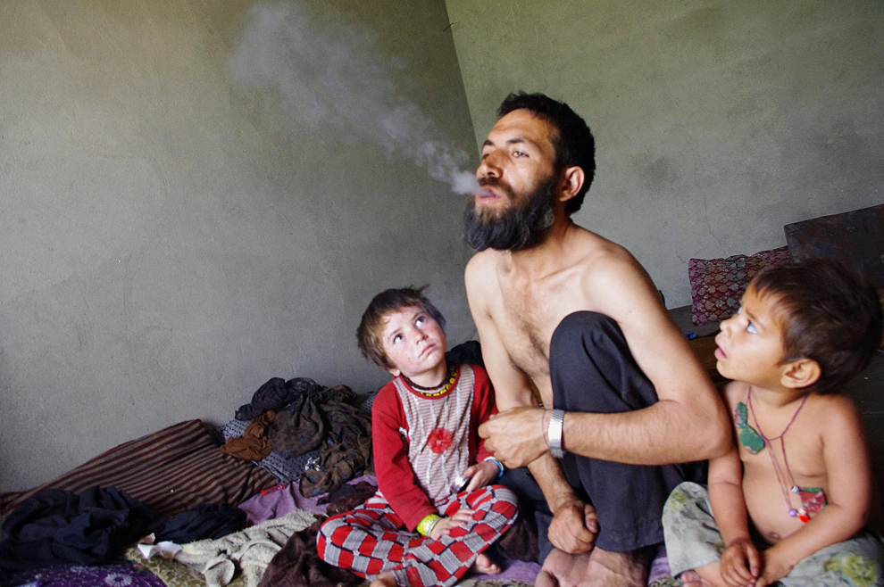 Un bărbat afgan dependent de droguri, Abdul Rahman, 44 ani, expiră fum după ce a inhalat opiu, în timp ce este privit de copiii săi, în casa lor din provincia Laghman, marţi, 21 mai 2013.