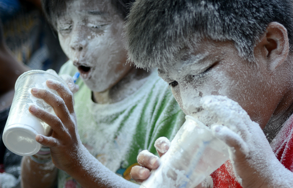 Copii suflă prin paie pentru a goli făină din pahare, în timpul unui concurs organizat cu ocazia sărbătorii anuale a Sf. Rita din Cascia, în Manila, Filipine, duminica, 19 mai 2013. 