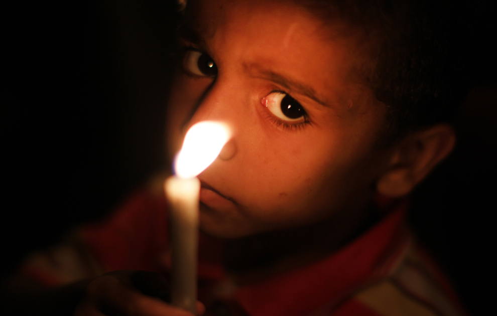 Un copil palestinian ţine o lumânare aprinsă în semn de solidaritate cu prizonierii palestinieni deţinuţi în închisorile israeliene, luni, 15 aprilie 2013.  
