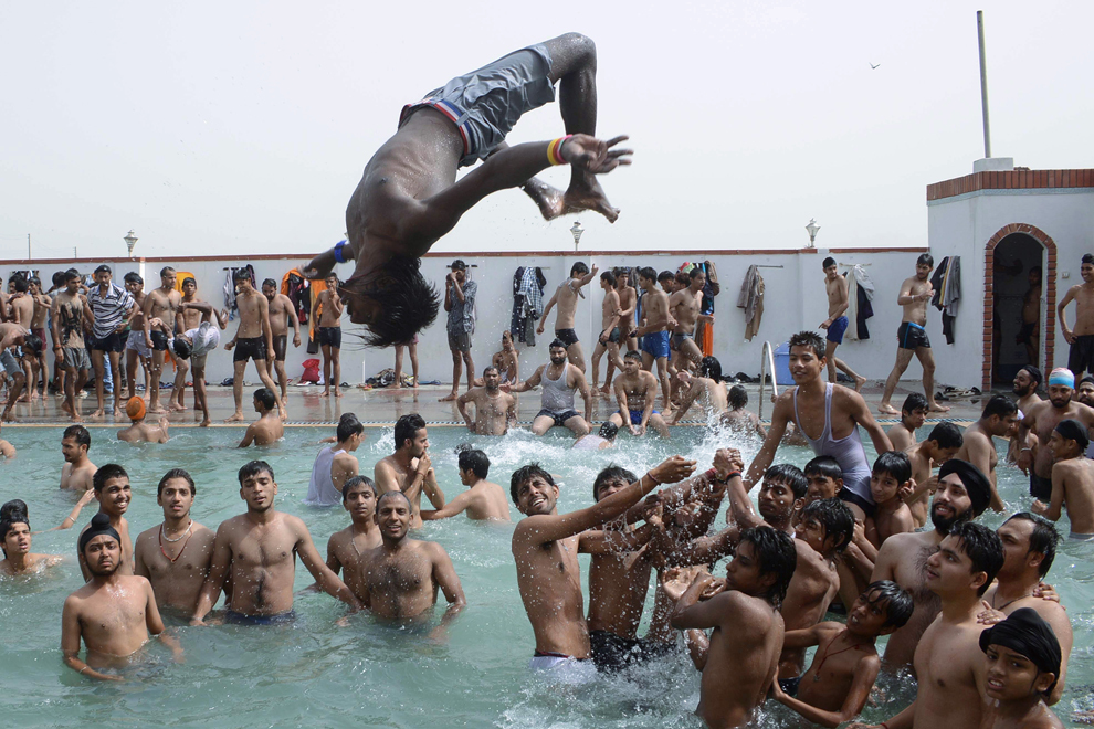 Un tânăr indian sare într-o piscină aflată la periferia oraşului Amritsar, duminică, 26 mai 2013. Venirea verii face ca temperaturile înregistrate în câmpiile din nordul Indiei sa se situeze în jurul valorii de 48 de grade Celsius.