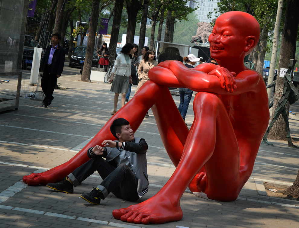 Un bărbat pozează lângă sculptura ‘Orizontul copilăriei’, aparţinând artistului Chen Wenling, expusă cu prilejul celor trei zile ale Târgului de Artă Contemporană Beijing, în Beijing, joi, 2 mai 2013. China are una dintre pieţele de artă cu cea mai mare creştere din lume, cumpărătorii chinezi devenind o prezenţă obişnuită a licitaţiilor internaţionale. 