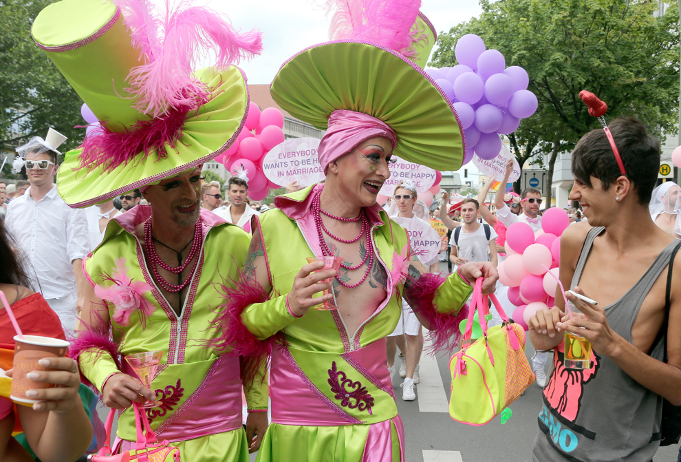 Participanţi îmbrăcaţi în haine colorate ţin în mână pahare de şampanie din plastic, în timpul paradei CSD (Cristopher Street Day Parade), în Berlin, sâmbătă, 22 iunie 2013. 