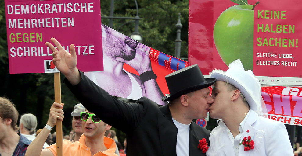 Doi bărbaţi costumaţi în miri se sărută în timpul paradei Christopher Street Day Parade, în Berlin, Germania, sâmbătă, 22 iunie 2013. 
