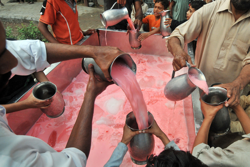 Voluntari pakistanezi distribuie băuturi dulci credincioşilor musulmani după încheierea postului din prima zi a Ramadanului, în Lahore, joi, 11 iulie 2013. 