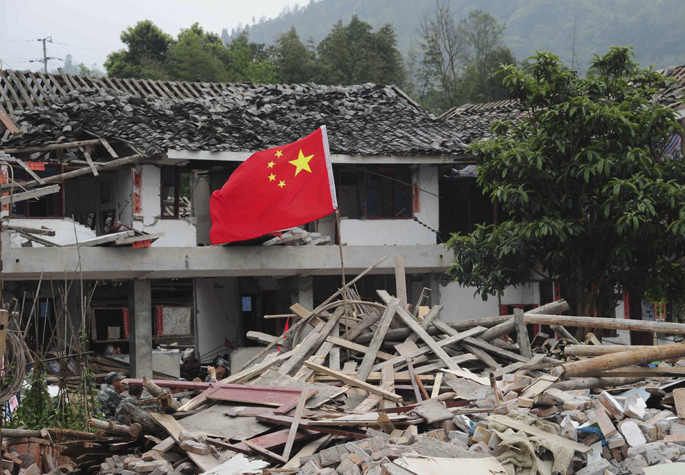 Drapelul Republicii Populare Chineze flutură printre ruinele caselor din oraşul Longmen, localitate aflată în apropierea epicentrului cutremurului produs în oraşul Ya’an, duminică, 21 aprilie 2013. 