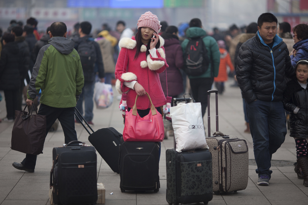 O femeie stă lângă bagajul ei în timp ce vorbeşte la telefonul mobil, în gara din Beijing, duminică, 27 ianuarie 2013. 