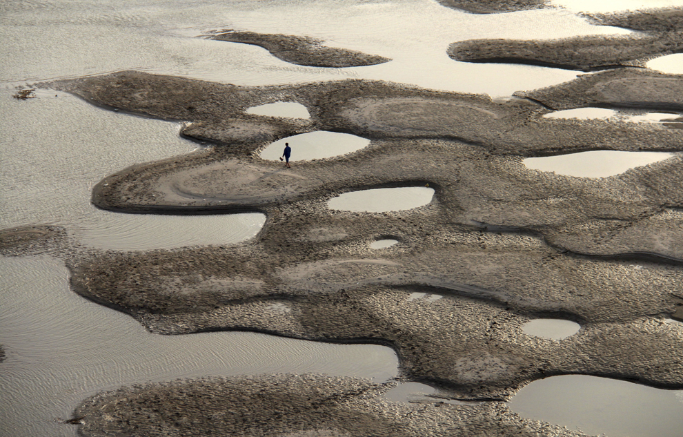 Un bărbat merge prin albia râului Hanjiang, în timpul sezonului secetos, în provincia Hubei, marţi, 9 aprilie 2013. 