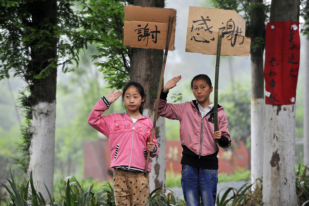 Doi copii salută şi afişează pancarte pe care stă scris “Vă mulţumim pentru serviciile de intervenţie”, pe o stradă din provincia Lushan, marţi, 23 aprilie 2013. 