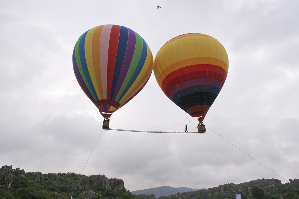 - Exelon Kyle, deţinătorul mai multor recorduri Guinness, merge pe o sârmă întinsă între două baloane cu aer cald, în Kunming, provincia Yunnan din sud-vestul Chinei, marţi, 30 iulie 2013. 