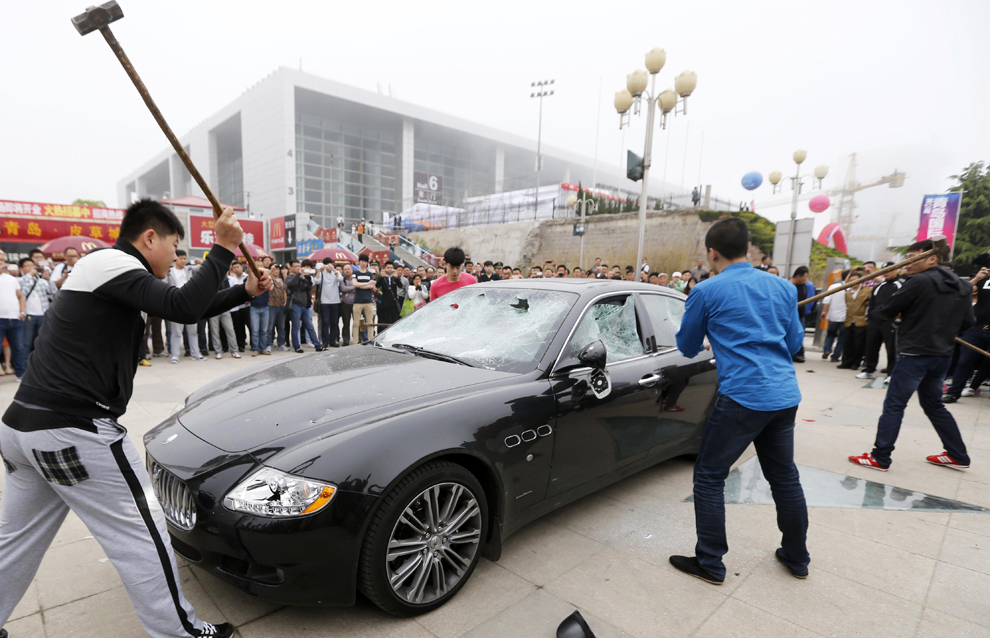 Patru barbaţi distrug, în semn de protest, o maşină Maserati, în vecinătatea unui complex expozitional ce găzduieşte ce-a de-a XII-a ediţie e Salonului Auto Qingado, în estul provinciei Shandong, marţi, 14 mai 2013. 