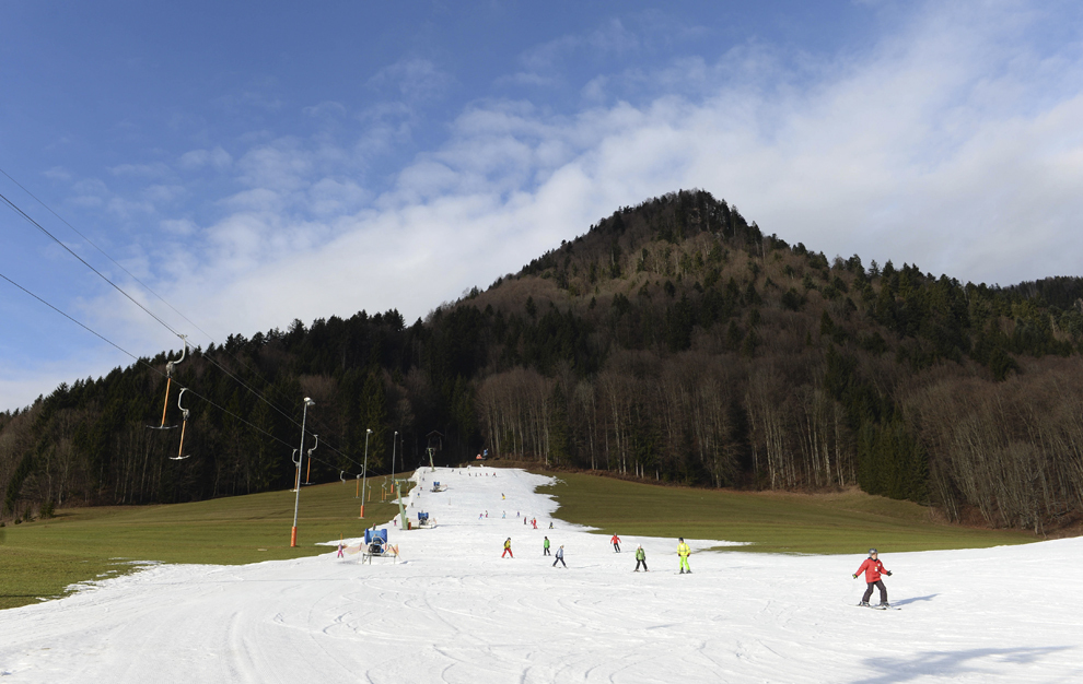 Copiii se dau cu schiurile pe un deal pregătit cu zăpadă artificială, miercuri, 8 ianuarie 2014, în apropiere de Ruhpolding, sudul Germaniei, unde temperaturile au ajuns la plus opt grade Celsius.