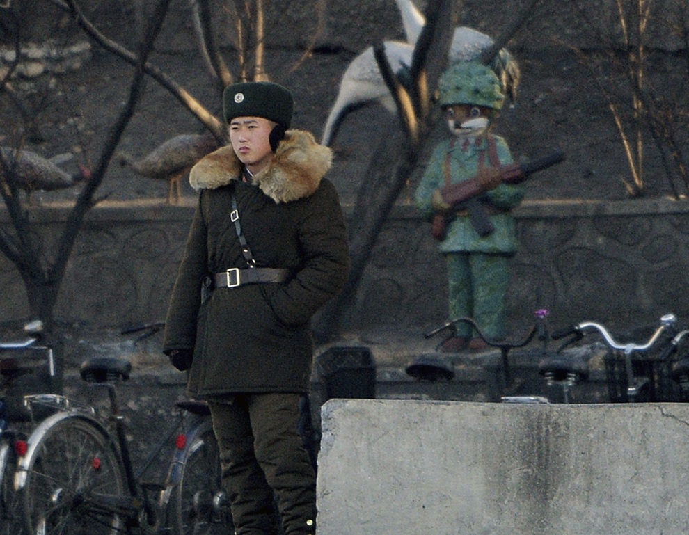 Un soldat nord-coreean (S) stă de pază pe malurile râului Yalu care separă oraşul nord-coreean Sinuiju de oraşul de frontieră chinez Dandong, în timpul celei de-a doua comemorări a morţii fostului lider Kim Jong-Il, marţi, 17 decembrie 2013.