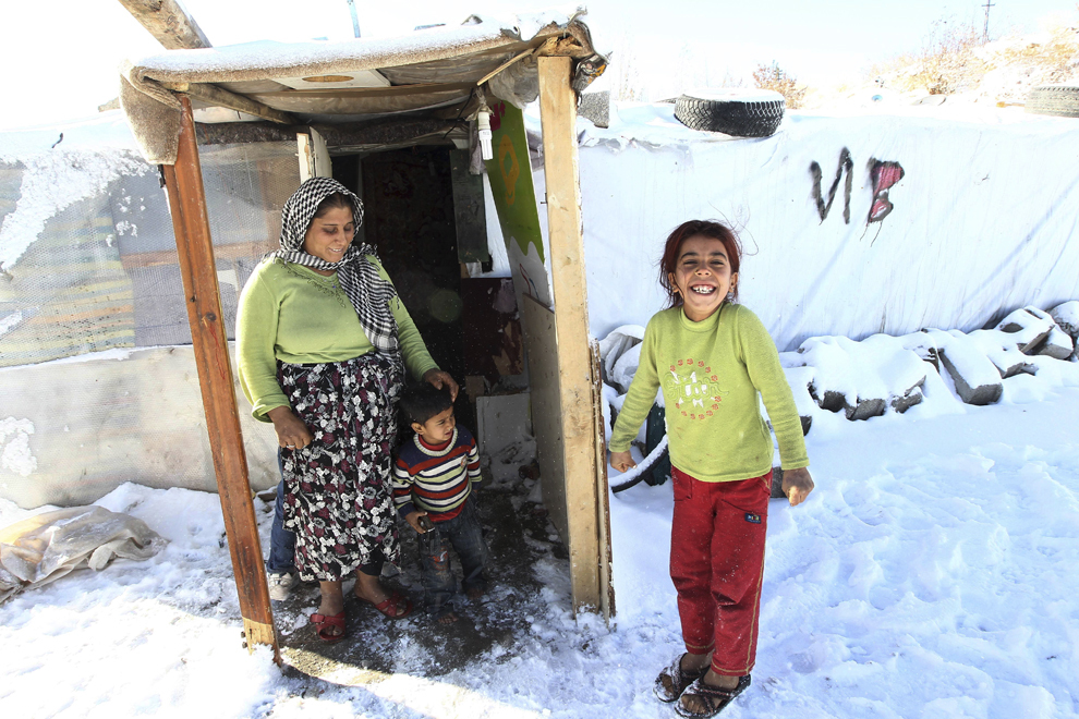 Refugiaţi sirieni stau în zăpadă în faţa casei lor improvizate dintr-un câmp pentru refugiaţi din Ankara, Turcia, duminică, 8 decembrie 2013.