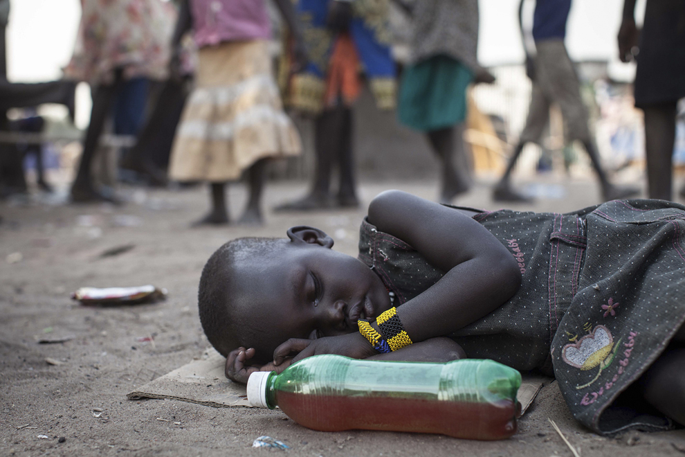 O fată doarme, în timp ce oamenii îşi văd de viaţa lor de zi cu zi în Minkammen, 25 km sud de Bor, Sudanul de Sud, miercuri, 8 ianuarie 2014. Războiul civil a izbucnit recent în această ţară.