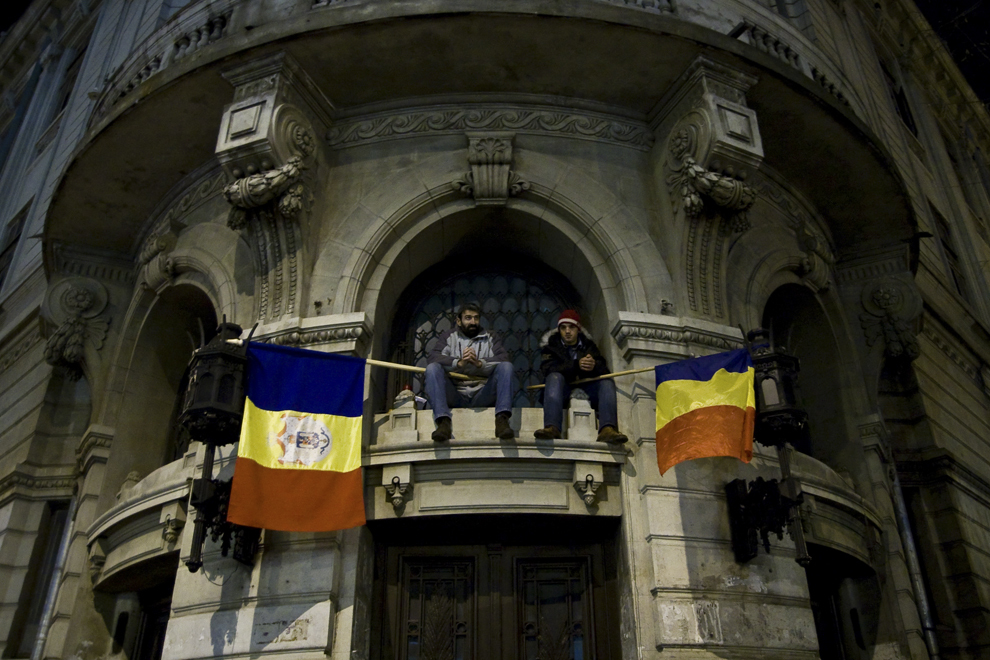 Doi bărbaţi stau deasupra intrării în Facultatea de Geografie, în cea de-a zecea zi de proteste în Piaţa Universităţii din Bucureşti, duminică, 22 ianuarie 2012.