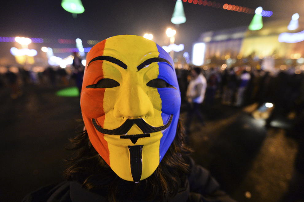 Un tânăr poartă o mască Guy Fawkes pictată în culorile tricolorului României, în timpul unui protest împotriva clasei politice, în Piaţa Victoriei din Bucureşti, sâmbătă, 21 decembrie 2013.