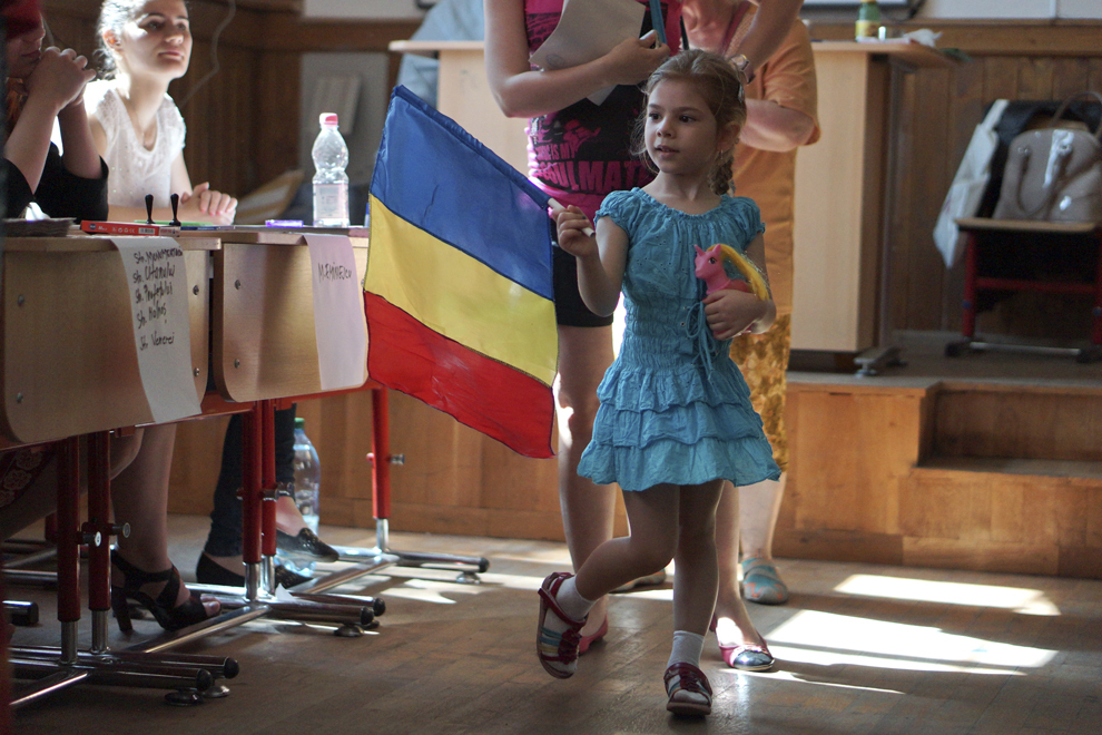 O fetiţă ţine într-o mână steagul României, alături de mama sa care votează pentru alegerile europarlamentare, la Colegiul Naţional Dimitrie Cantemir din Bucureşti, duminică, 25 mai 2014.