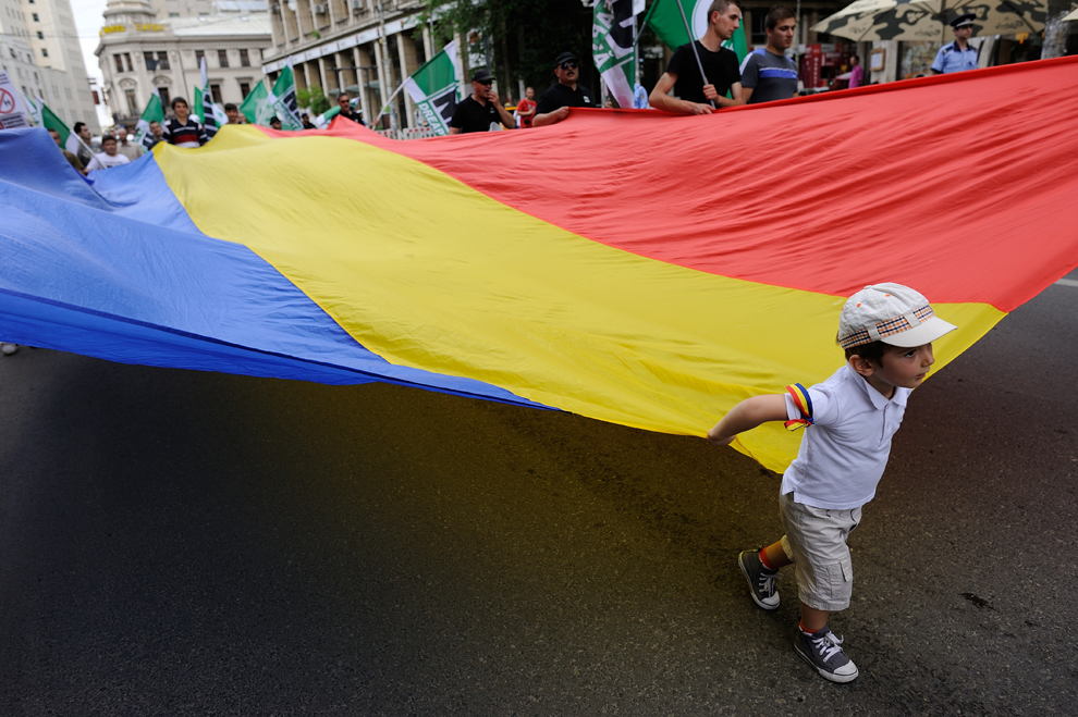 Un copil ţine împreună cu participanţii la "Marşul pentru Normalitate" un steag naţional imens, în timpul mitingului organizat de Noua Dreaptă, prin care aceştia militează împotriva diversităţii sexuale şi a practicilor homosexuale, în Bucureşti, sâmbătă, 7 iunie 2014.