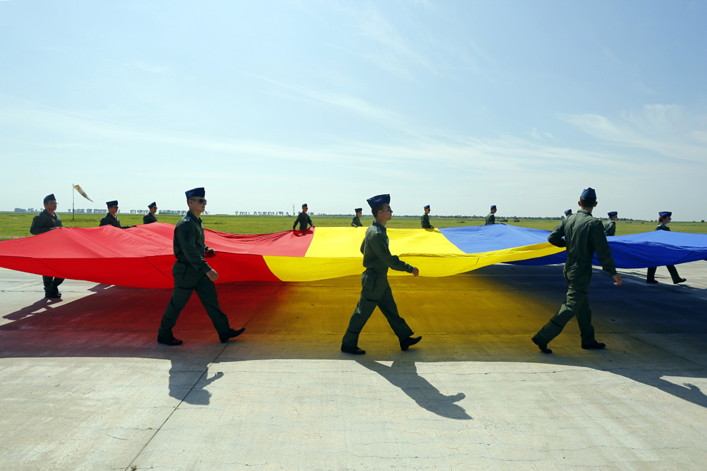 Militari poartă un drapel tricolor în deschiderea mitingului aviatic BOBAS 2014, la Şcoala de Aplicaţie pentru Aviaţie de la Boboc, Buzău, sâmbătă, 14 iunie 2014.
