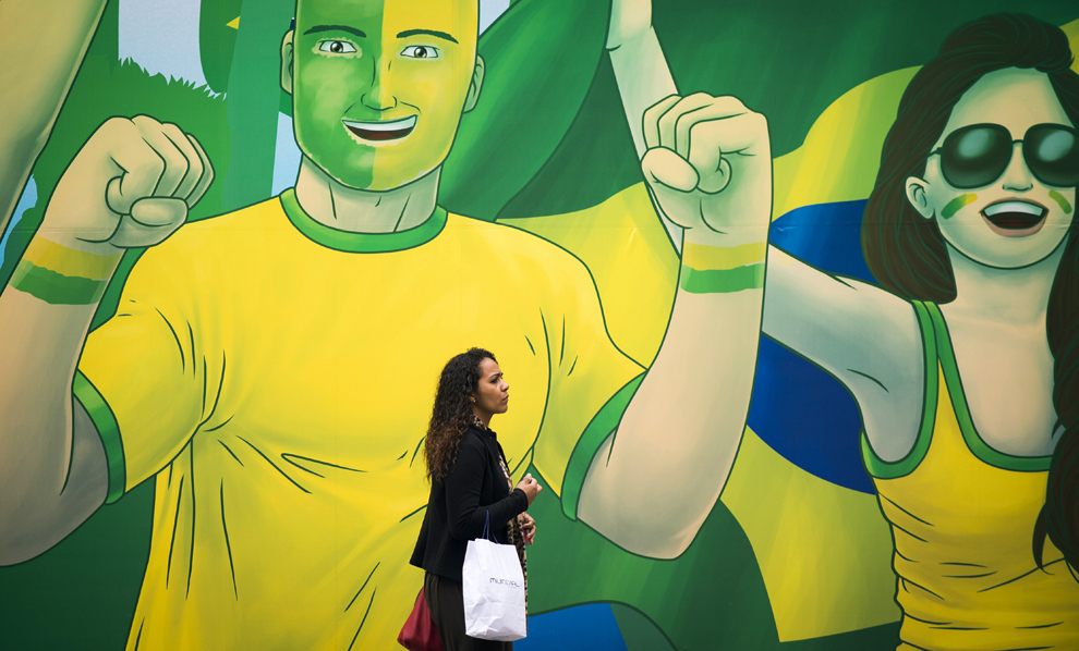 O navetistă pe lângă o pictura murală în care sunt înfăţişaţi suporteri ai fotbalului, in Sao Paolo, Brazilia, 11 iunie 2014.