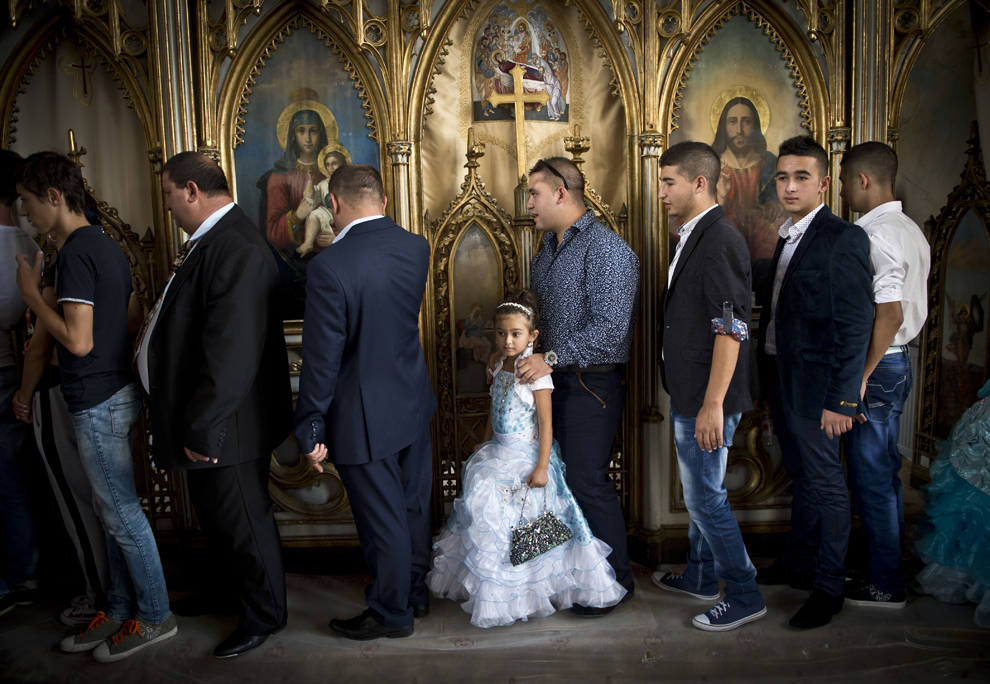 Mai mulţi romi de naţionalitate română stau la rând lângă icoane ortodoxe, pentru a trece pe sub o masă, în timp ce participă la un serviciu religios, cu ocazia reuniunii anuale a romilor, cu ocazia sărbătorii Naşterii Maicii Domnului, în Costeşti, Vâlcea, luni, 8 septembrie 2014.