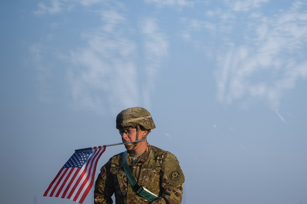 Un soldat  american prinde drapelul Statelor Unite ale Americii pe antena unui transportor militar blindat “Stryker”, în baza militară Mihail Kogalniceanu, miercuri, 13 mai 2015.