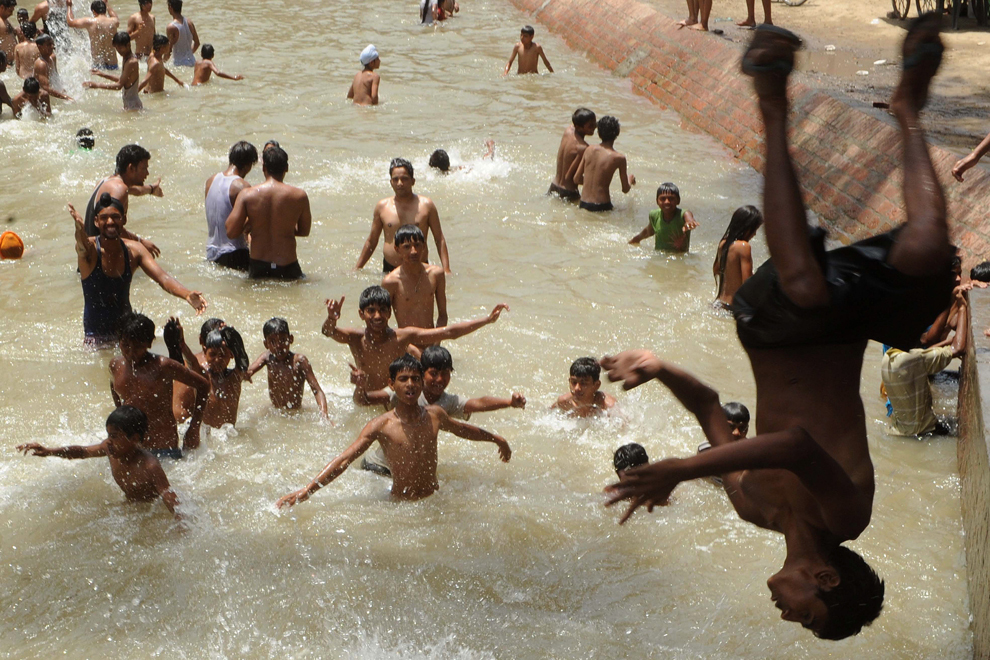 Tineri indieni se răcoresc în apa unui canal din Amritsar, duminică, 17 iunie 2012. Valul de căldură persistă în mare parte din nordul Indiei, în timp ce musonul, vital pentru fermieri, a atins coasta sud-vestică pe 5 iunie, cu o intârziere de 4 zile. 