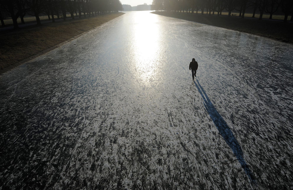 Un bărbat merge pe un lac îngheţat din Cologne, luni, 6 februarie 2012. Valul de frig care a cuprins Europa de mai mult de o săptămână a produs haos pe întregul continent, solicitând la maxim serviciile de urgenţă, anulând zboruri şi producând mai mult de 300 de decese. 