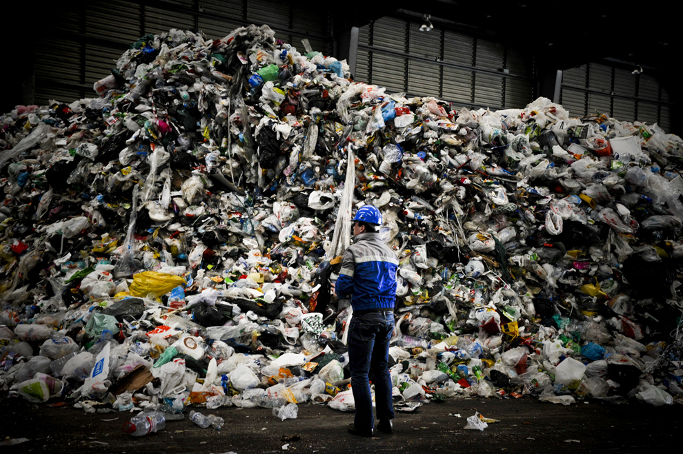 Un muncitor stă în faţa unui morman de gunoi ce urmează a fi reciclat, la Valorsul, o uzina de reciclare a deşeurilor, în Lisabona, marţi, 22 ianuarie 2013. 