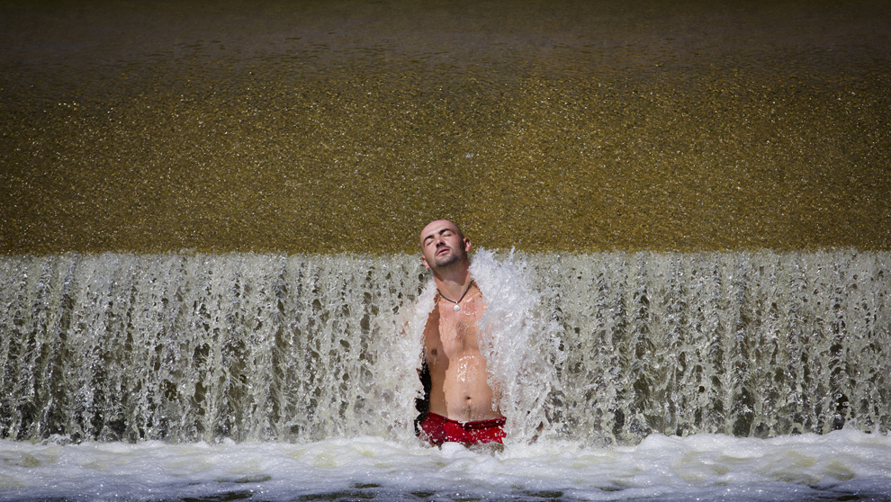 Un tânăr se relaxeaza la barajul râului Berounka, în apropiere de Dobrichovice, Cehia, duminică, 28 iulie 2013. 