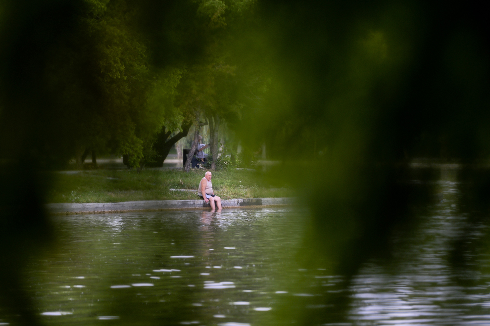 Un bărbat se relaxează, pe malul lacului din parcul I.O.R din Bucureşti, luni, 29 iulie 2013.